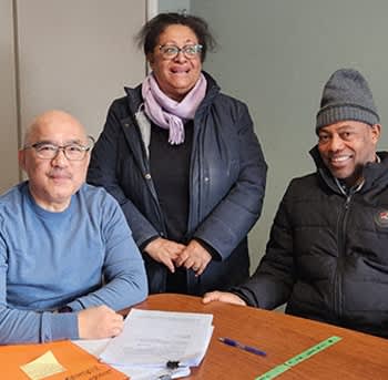 three people sitting at a table with paperwork