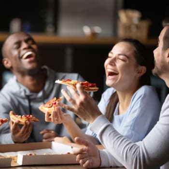 a group of people laughing while eating pizza