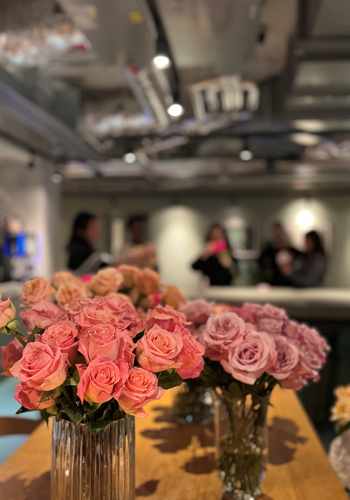 Two vases of pink roses on a table.