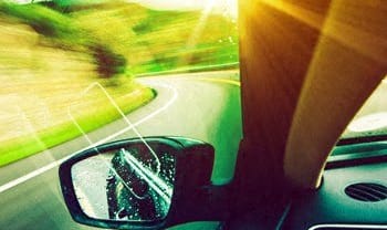 a view of the side mirror of a car driving down a road