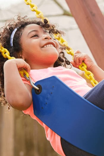 a young girl is swinging on a playground swing