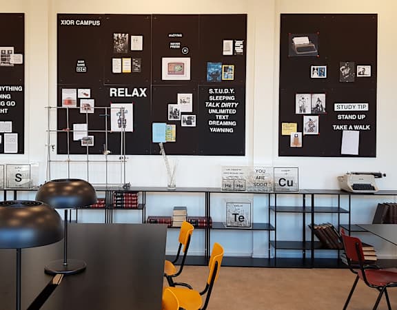 a room with tables and chairs and posters on the wall