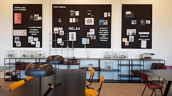a room with tables and chairs and posters on the wall