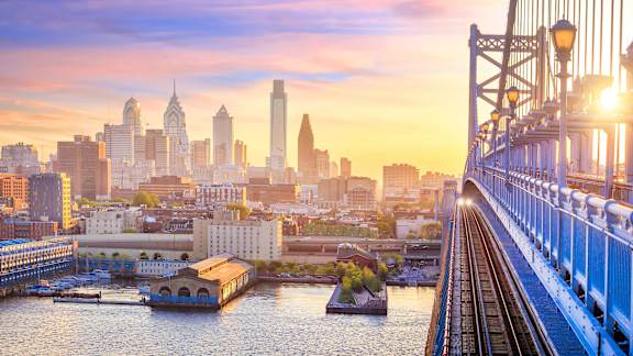 A city skyline at sunset with a bridge in the foreground.