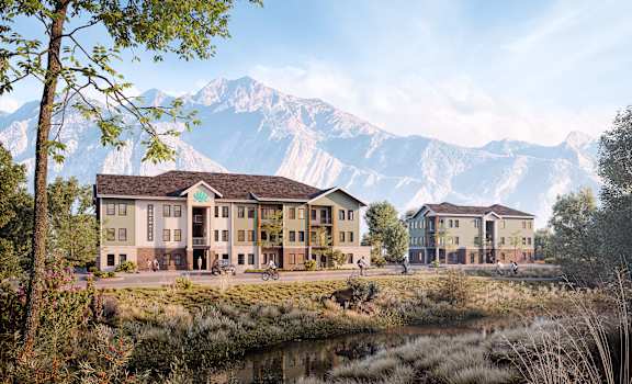 A large building with a brown roof is situated in front of a mountain range.