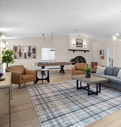 A living room with a grey couch and a blue rug.