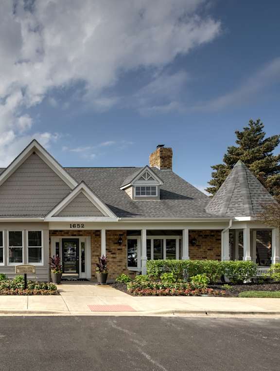 A grey house with a black roof and a chimney.