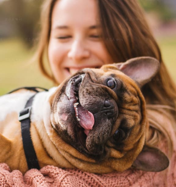 a woman holding a white dog with its tongue out