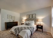 Thumbnail 5 of 26 - A bedroom with a bed, nightstands, and pictures on the wall.