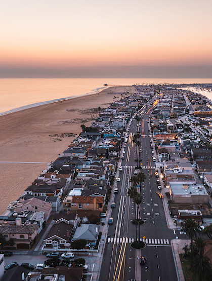 A beachfront street with buildings on either side and a body of water in the background.