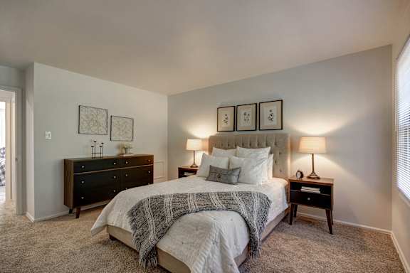 A bedroom with a bed, nightstands, and pictures on the wall.