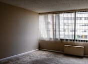 Thumbnail 2 of 2 - A room with a window covered by blinds and a radiator on the floor at Hampton Plaza Apartments, Towson, MD, 21286