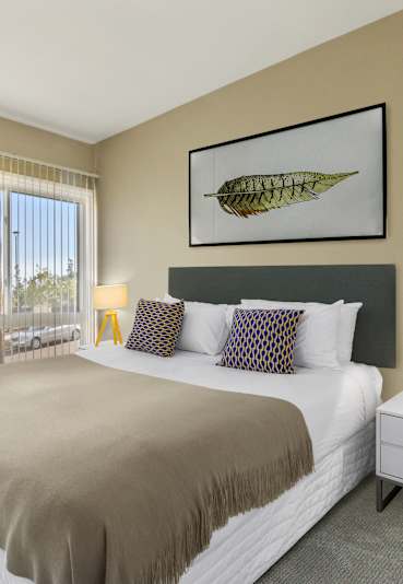 A bedroom with a large bed and a chair.