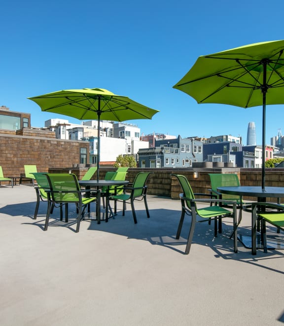 a patio with green chairs and umbrellas on top of a building