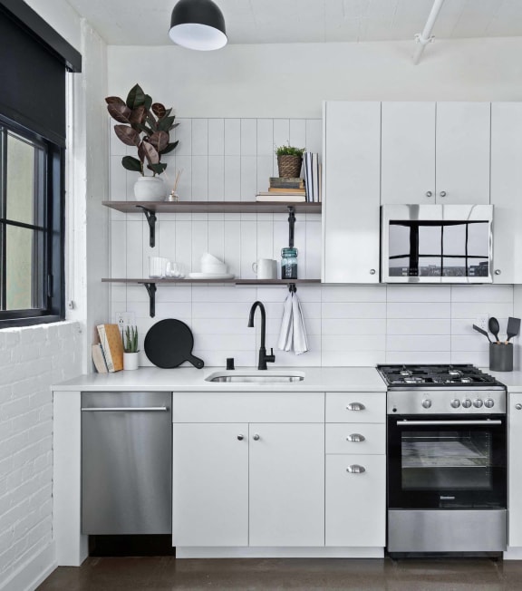 a white kitchen with stainless steel appliances and white cabinets