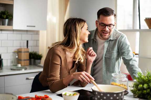 A man and a woman are cooking together in a kitchen.