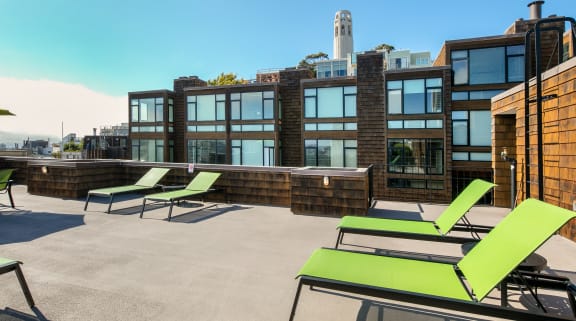 a rooftop deck with lounge chairs and a fire pit