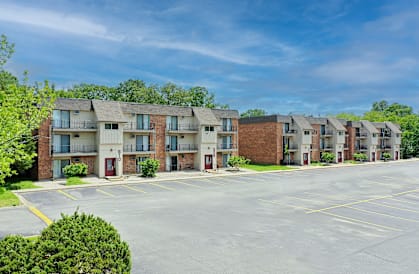 A row of apartment buildings with a parking lot in front.