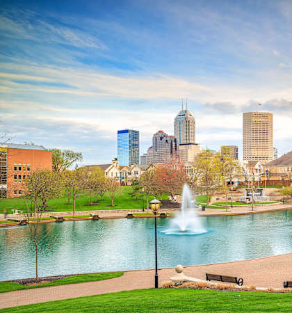 a park with a lake and fountain and a city in the background