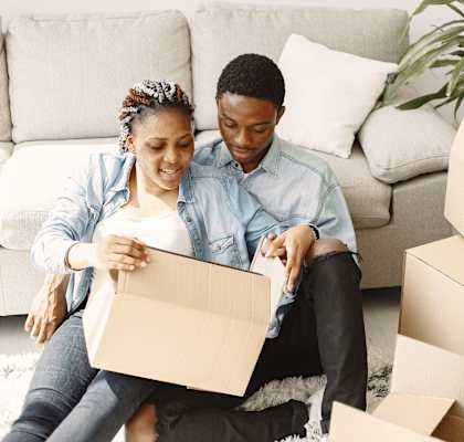 A couple sitting on the floor surrounded by moving boxes at Woodside Village Apartments, Clarkston, 30021