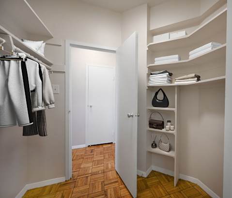 A hallway with a white door and a white closet with a shelf and a black speaker.