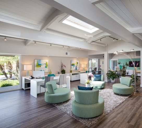 A spacious room with green chairs and wooden floors.
