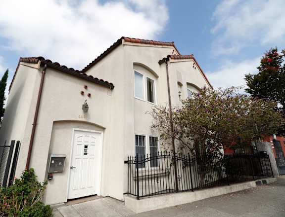 A white house with a black gate and a brown roof.