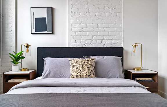 a bedroom with a bed and a white brick wall