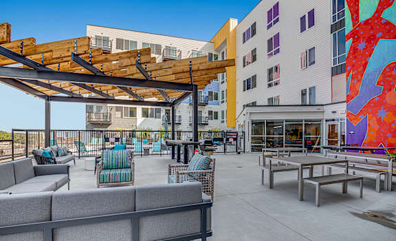 a patio area with tables and chairs and a large mural