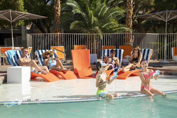 People are relaxing by the poolside on a sunny day.