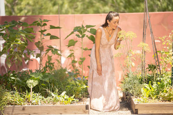 A woman in a white dress is standing in a garden.