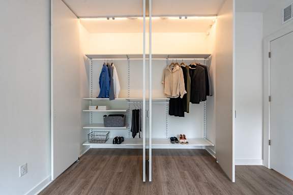 A walk in closet with clothes hanging and shelves.at Essen Apartments, Virginia