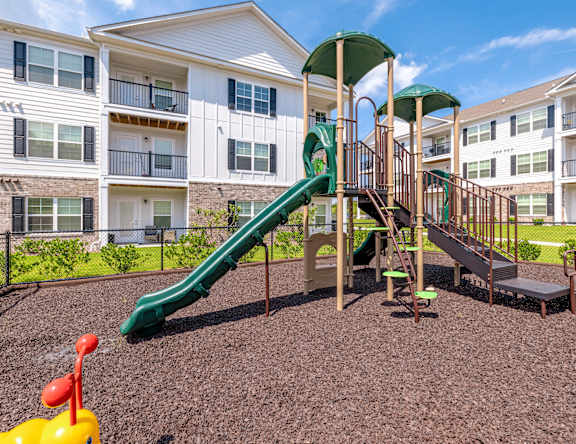 A playground with a green slide and a yellow duck toy.