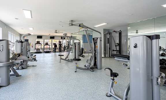 A gym with a variety of equipment including treadmills, weights, and exercise machines.