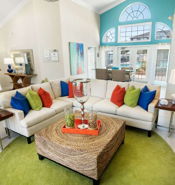 A living room with a white couch and a green rug.