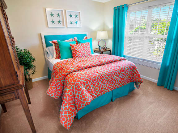 A bedroom with a bed covered in a red and white patterned comforter.