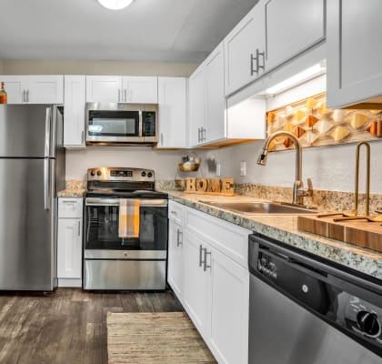 a kitchen with white cabinets and stainless steel appliances  at Castilian Apartments, Florida