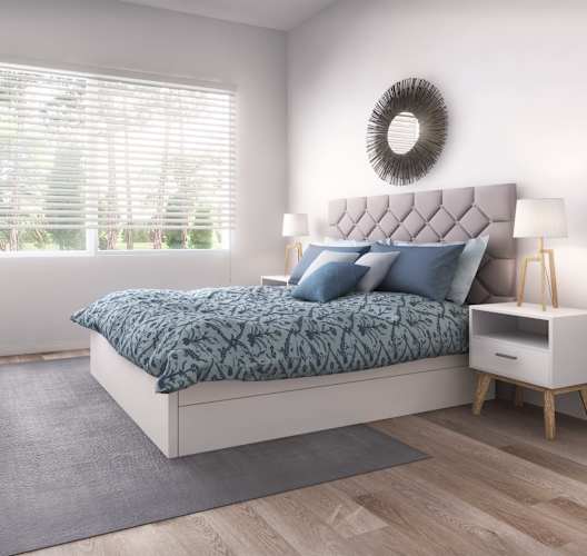 a bedroom with a bed with blue pillows and a grey rug