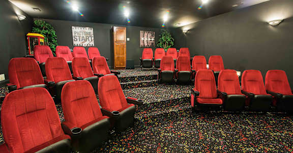 A cinema room with red seats and a sign that says "PICTURE START".