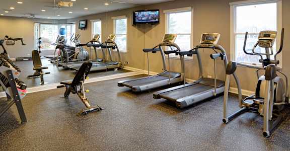 A gym with treadmills, exercise bikes, and a television.