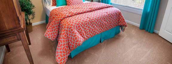 A bedroom with a bed covered in a red and white patterned comforter.