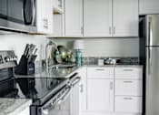 Thumbnail 2 of 4 - A modern kitchen with white cabinets and a black countertop at Hampton Plaza Apartments, Towson, MD, 21286
