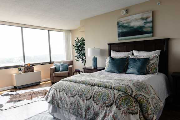 A bedroom with a large bed and a painting on the wall at Hampton Plaza Apartments, Towson, MD, 21286