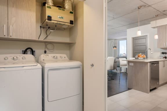 a white washer and dryer in a laundry room next to a kitchen with