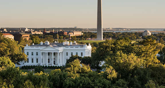The White House is seen from a distance with the Washington Monument in the background.