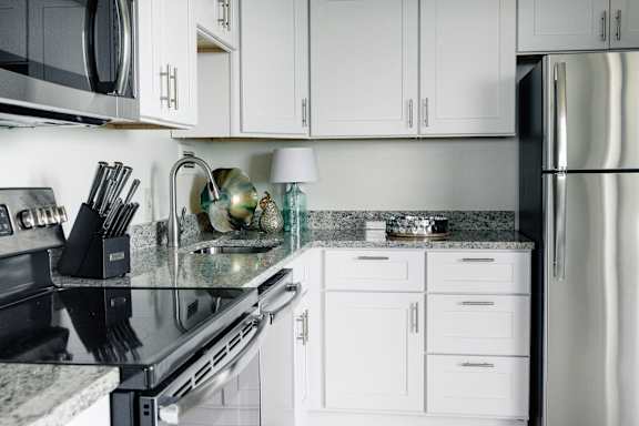 A modern kitchen with white cabinets and a black countertop at Hampton Plaza Apartments, Towson, MD, 21286