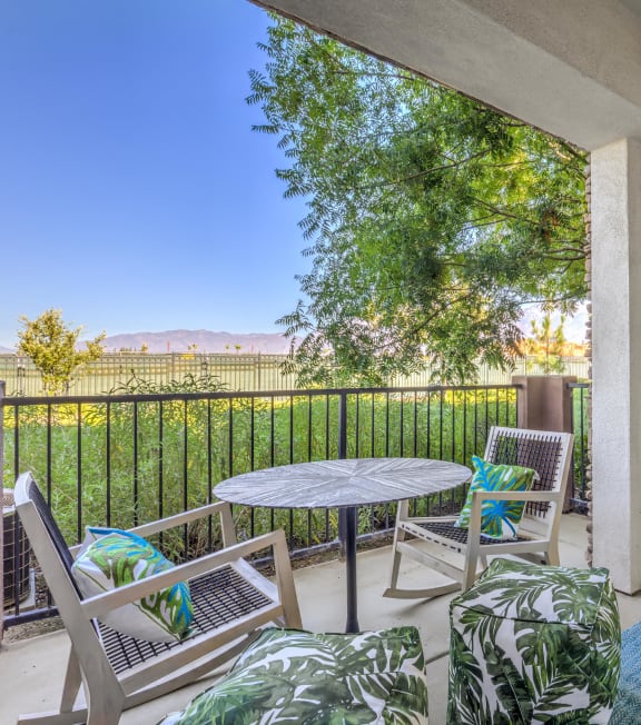 a patio with a table and chairs and a fence