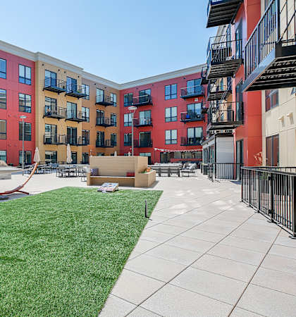 a courtyard with a hammock and a picnic table in front of an apartment building