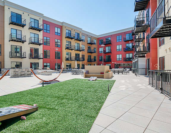a courtyard with a hammock and a picnic table in front of an apartment building