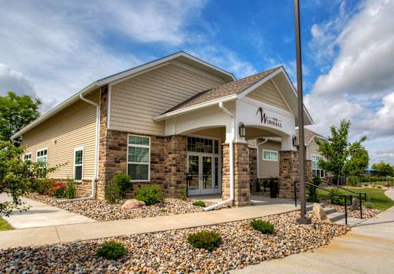 the front of a building with a stone facade and a sign on the side of at The Winhall of Williams Pointe Apartments, Waukee